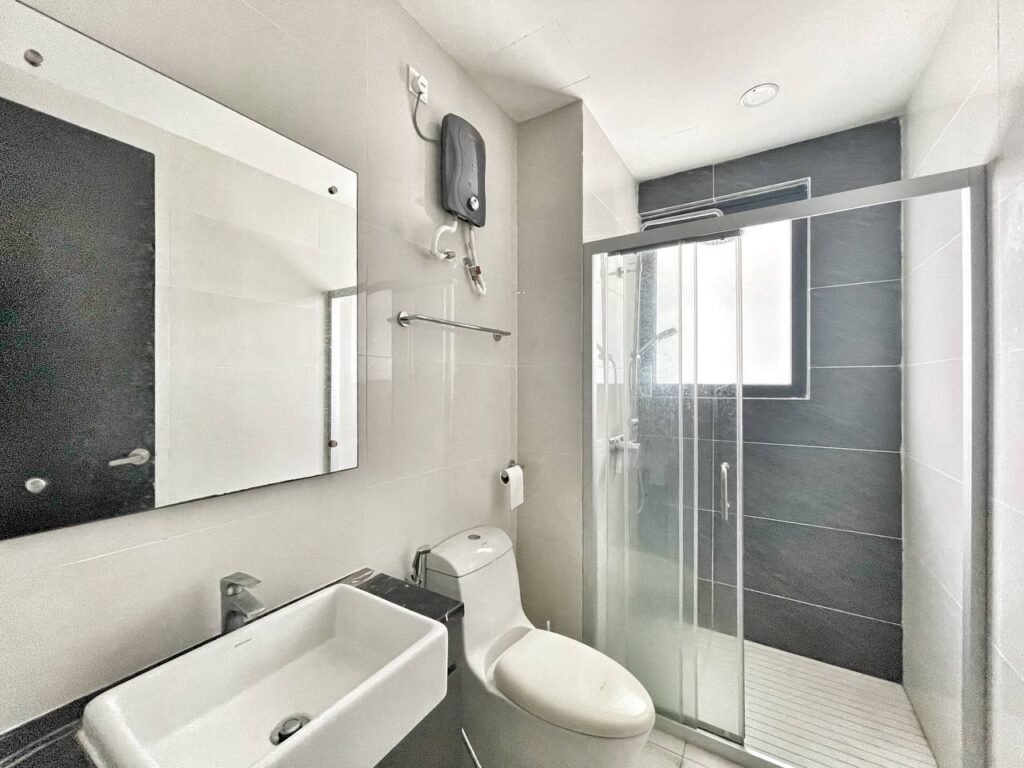 Bathroom with shower enclosure, toilet, sink, and water heater.