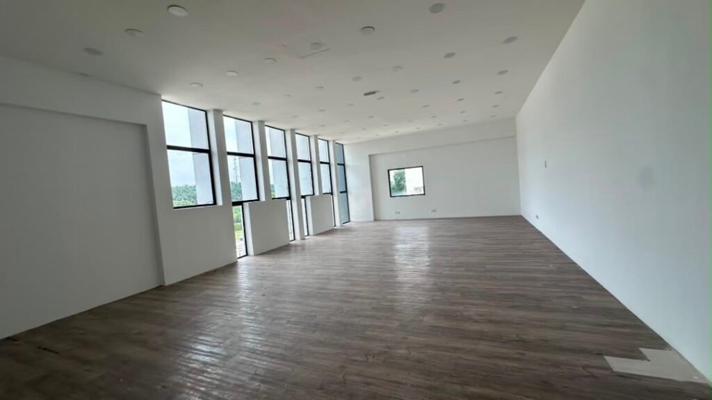 Spacious interior with tall windows, white walls, and wood-look flooring