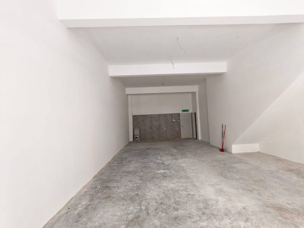 Long, empty commercial interior with exposed floor and rear wall.