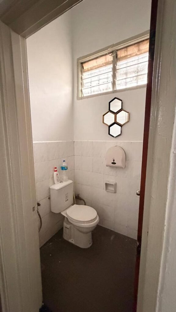 A compact tiled restroom with a toilet and a small window.