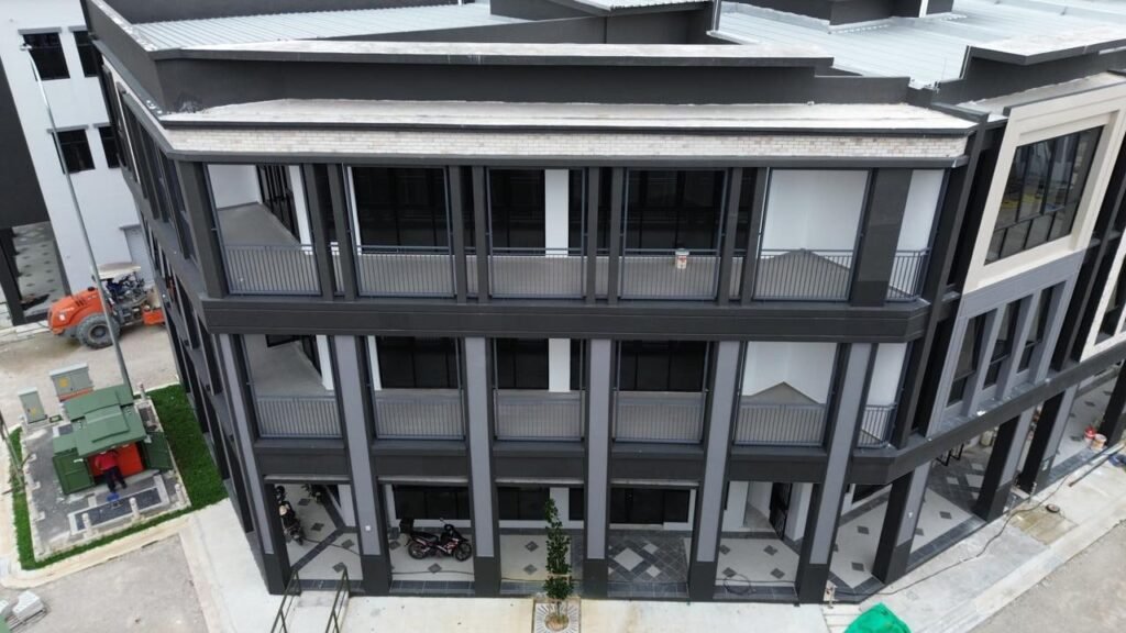 Close exterior view of a dark фасade corner shoplot block with balconies and ground-floor frontage.