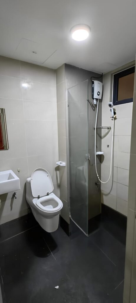 Bathroom with toilet, shower area, and sink.