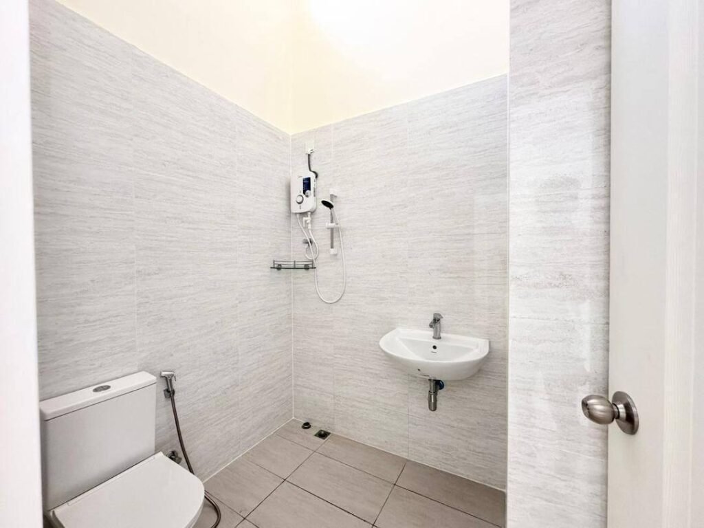 Bright tiled bathroom with toilet, sink, and shower fixture