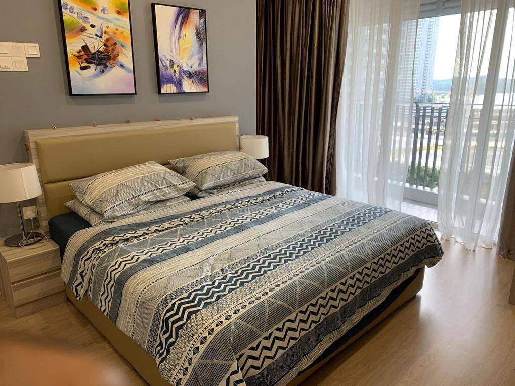 A furnished bedroom with a double bed, bedside lamps, wall art, and a balcony door with sheer curtains.