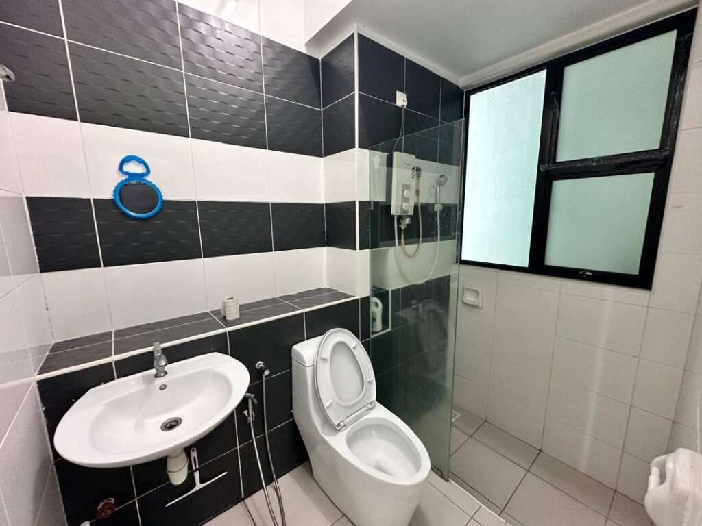 Bathroom with tiled walls, sink, toilet, shower area and frosted window.