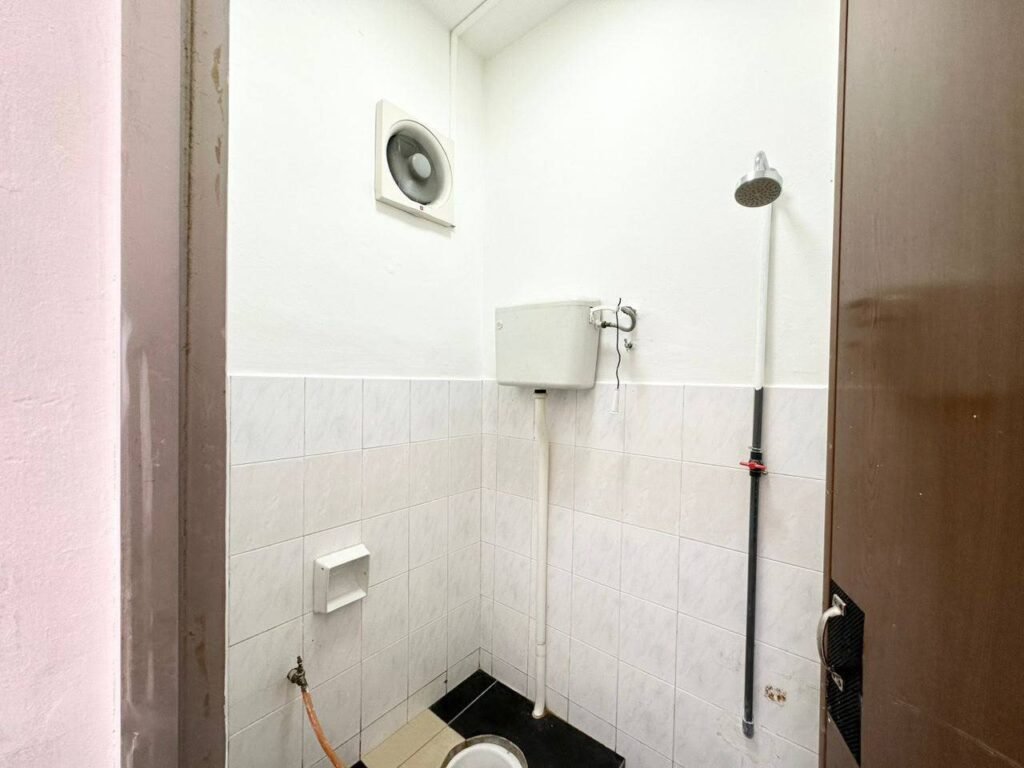 Bathroom with tiled walls, toilet, shower fixture, and visible plumbing.