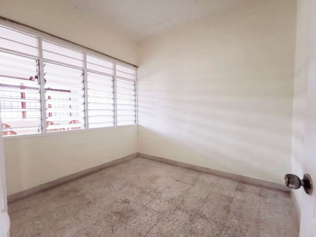 Empty bedroom with barred windows and tiled floor.