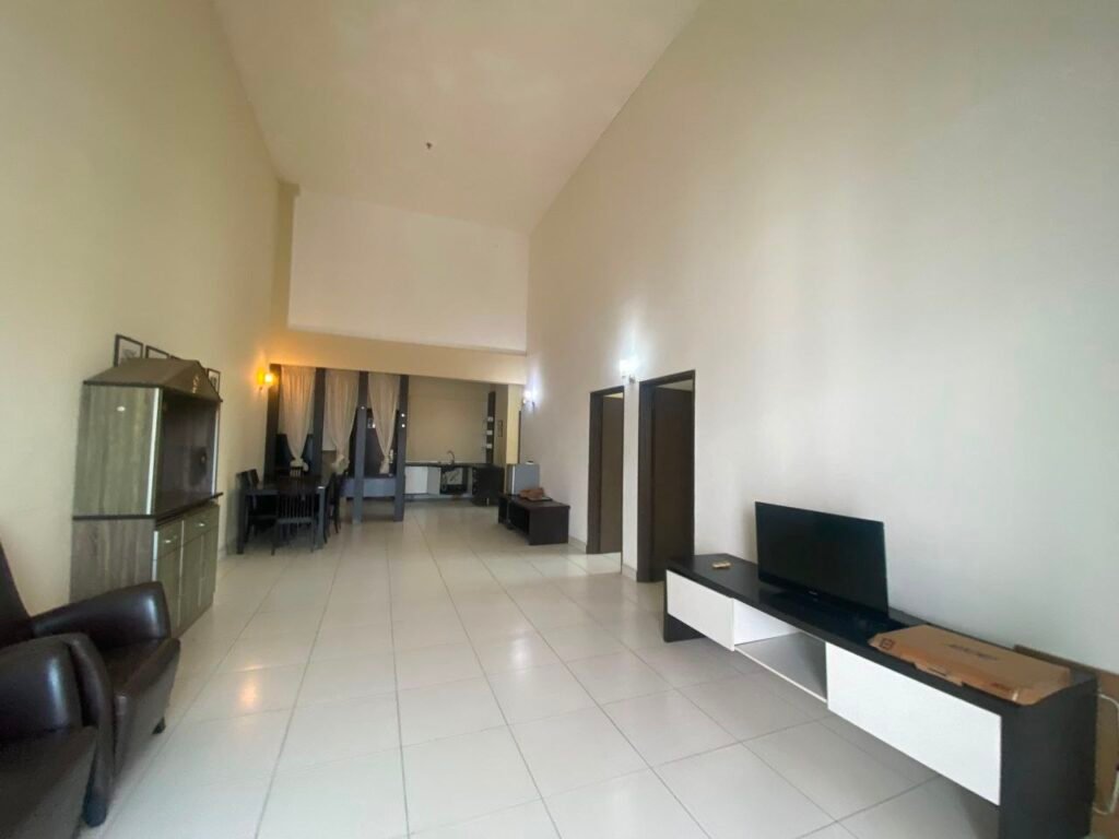 Long living space showing dining area, TV console and kitchen in the background