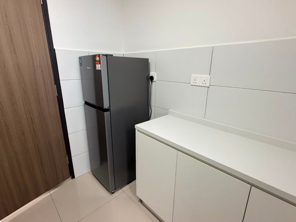 Compact kitchen area with refrigerator and white cabinet.