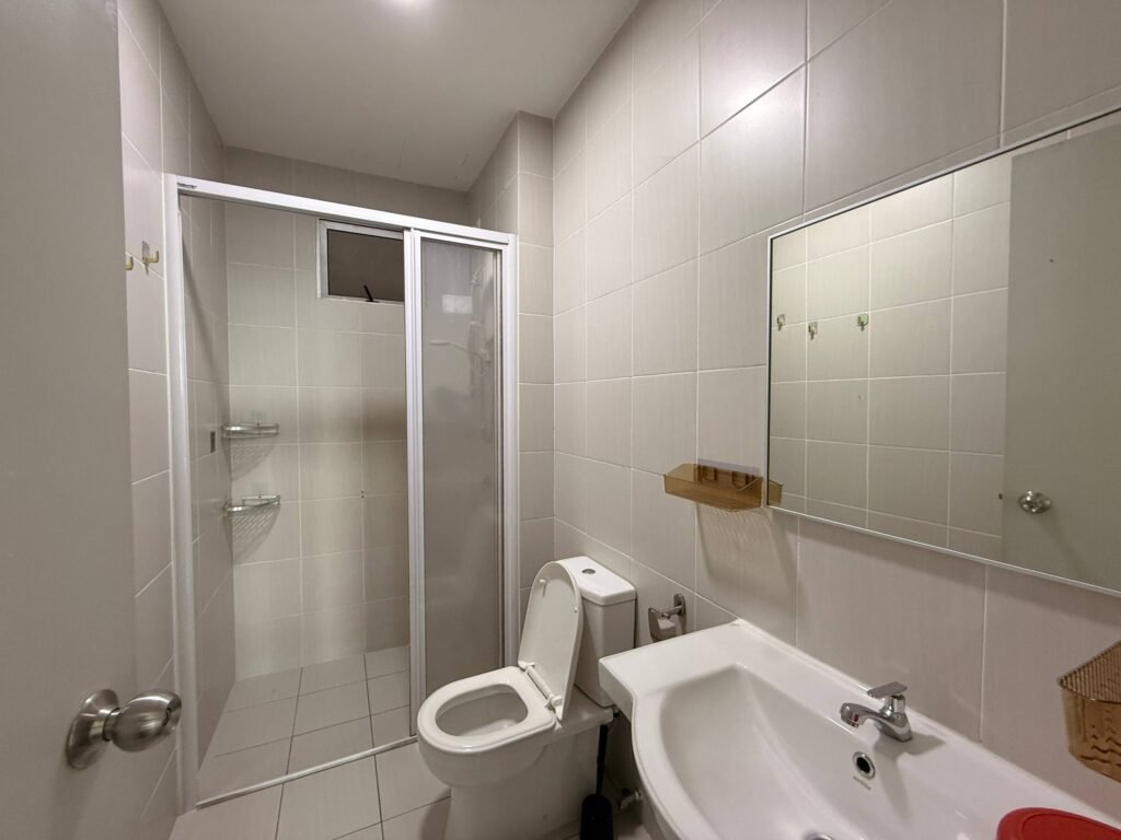 A tiled bathroom with shower enclosure, toilet, sink, and wall mirror.