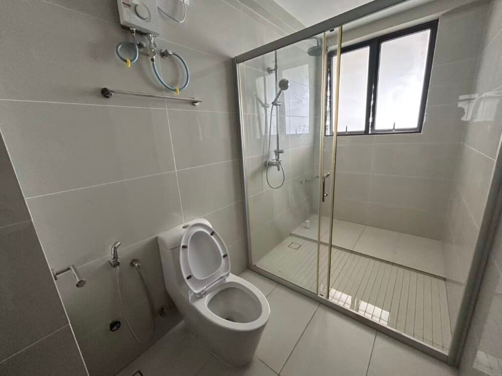 A modern bathroom with a glass shower enclosure, toilet, and tiled walls.
