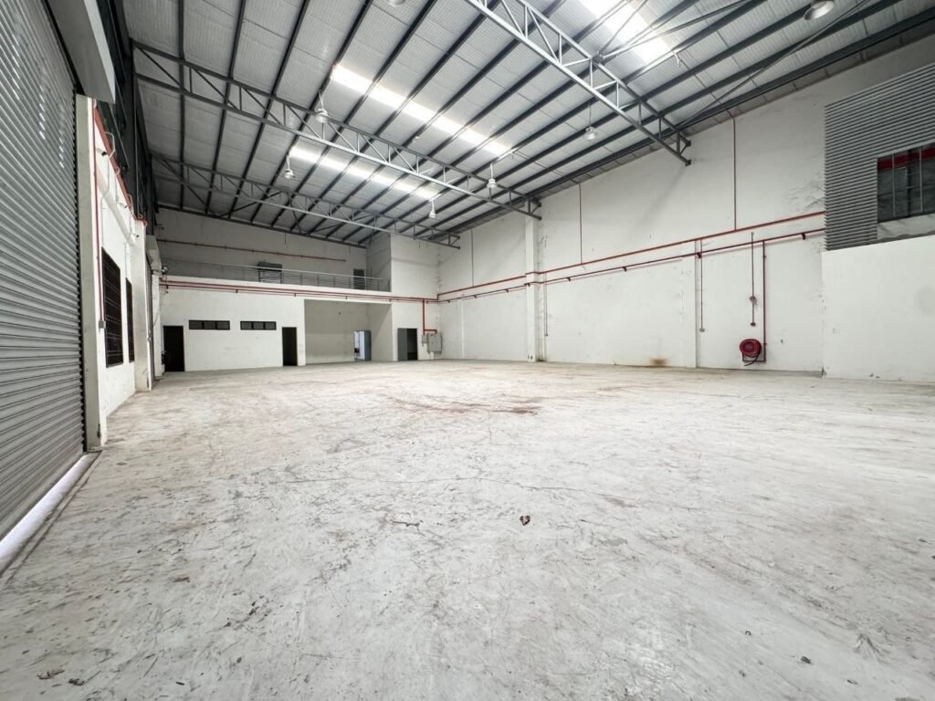 Another wide interior view of the same vacant industrial hall with steel roof trusses and concrete floor