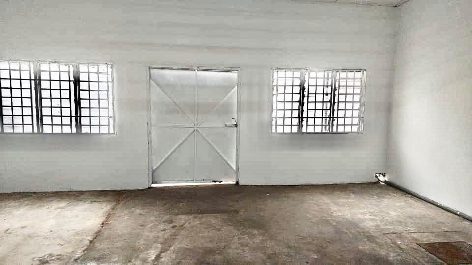 Interior industrial space with concrete floor, windows and metal door