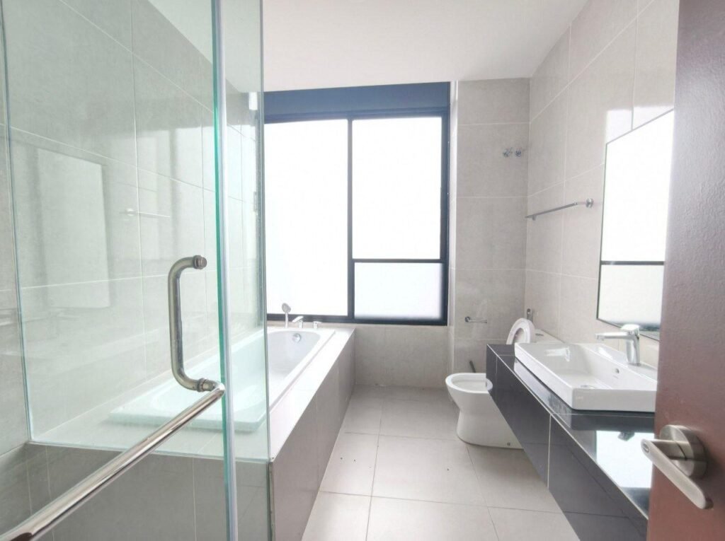 A bright bathroom with a bathtub, shower enclosure, vanity sink, and frosted window.