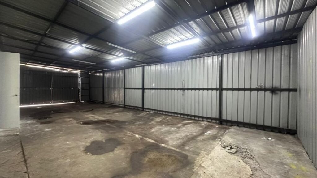 Industrial interior with corrugated metal walls, roof lights, and concrete floor
