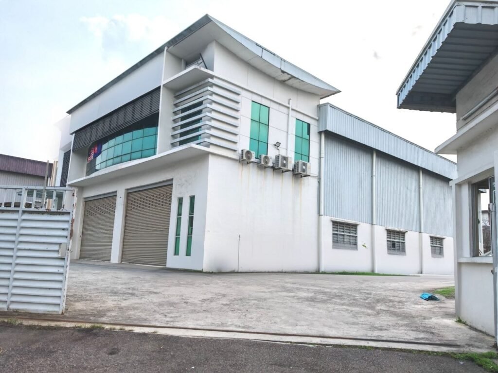 Exterior view of a detached factory building with shutter doors and industrial facade