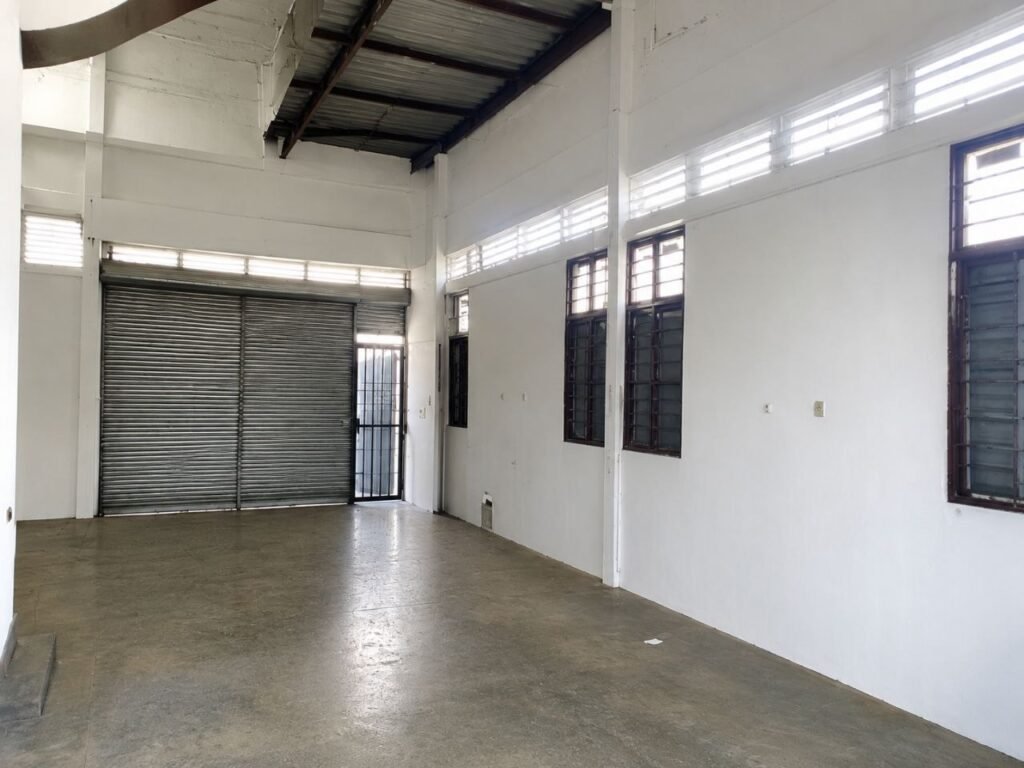 Interior industrial space with high ceiling, roller shutter door and side windows