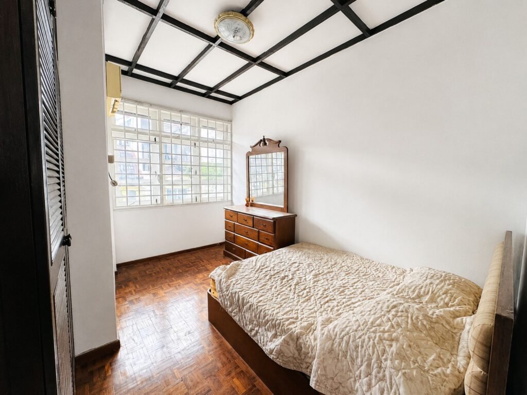 A bright bedroom with a bed, dresser, and window.