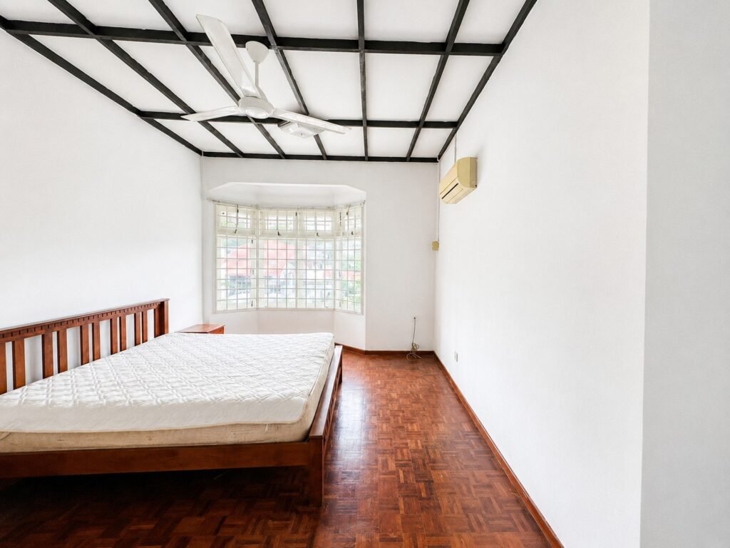 A bedroom with a bed, desk, and large window.