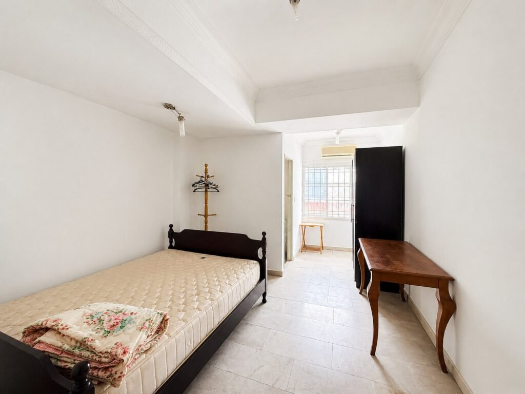 A bedroom with a bed, wardrobe, desk, and window.