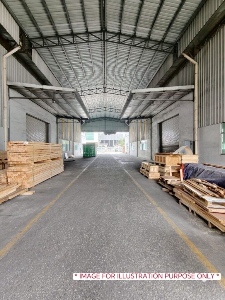 Long covered accessway inside an industrial property with materials stored along the sides